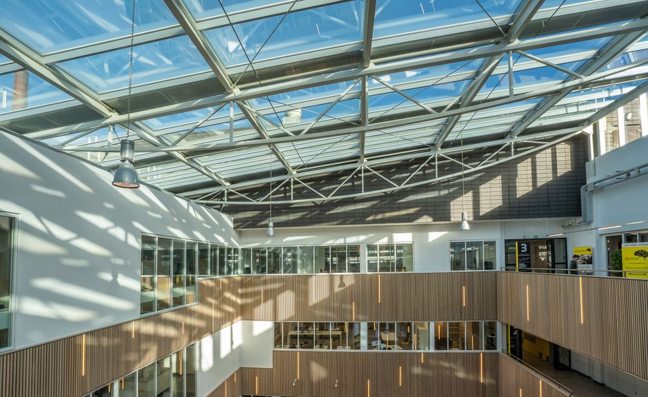 Spacious modern atrium showcasing a glass ceiling with sunlight shadows.