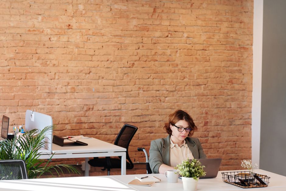 Businesswoman sitting at a desk in a stylish office using a laptop for remote work.
